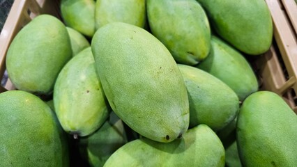 a pile of green mangoes display in supermarket, tropical fruits