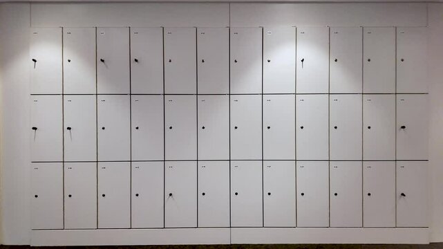 Wall of numbered office lockers, some showing keys and keyholes, providing secure storage for employees