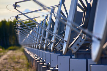 A row of solar radio telescope dishes against a forest background
