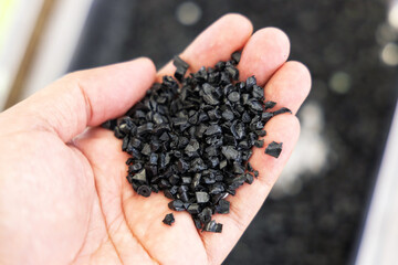 Close-up microplastics black from plastic waste on human hand. Plastic scraps from waste materials...