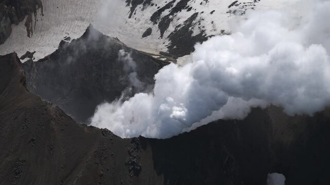 Winter mountains in clouds and bursts of steam from fumaroles