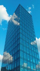 Fototapeta premium Modern office building with glass facade on a clear blue sky background, blue heavens, clouds