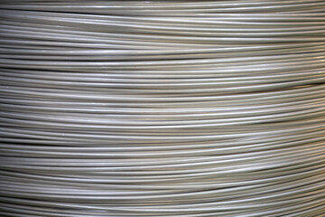 Close-up of coiled aluminum wires, highlighting their smooth surface and layered overlapping...
