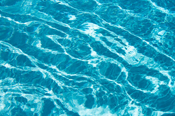 Water background. Blue water, ripples and highlights. Texture of water surface and tiled bottom.