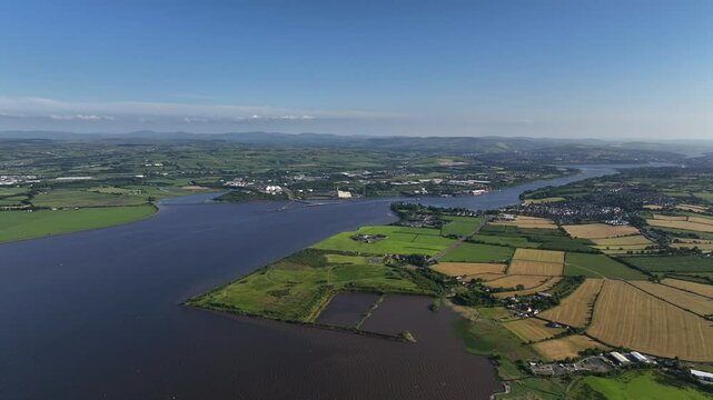 Lough Foyle, County Donegal, Ireland, June 2023. Drone in panoramic high-angle view, with Derry town in the distance as the River Foyle estuary opens out into a lake under a clear blue sky.