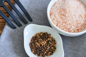 Himalayan salt and black pepper in white bowl on wooden table