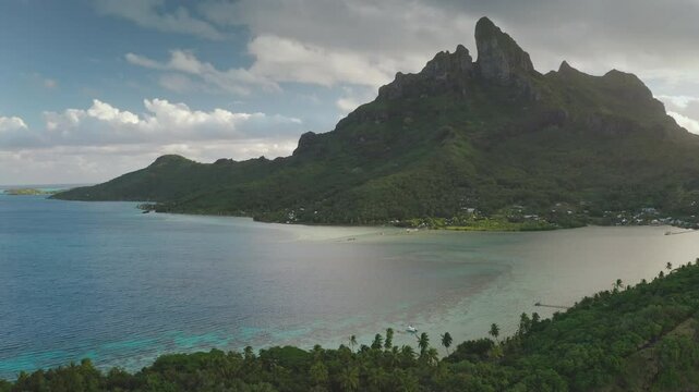 Majestic mount otemanu dominates bora bora island's skyline, its verdant slopes meeting the crystal-clear turquoise waters of a tranquil lagoon, creating a breathtaking tropical panorama