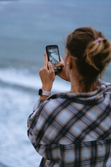 Woman traveler taking photos on the edge of a cliff