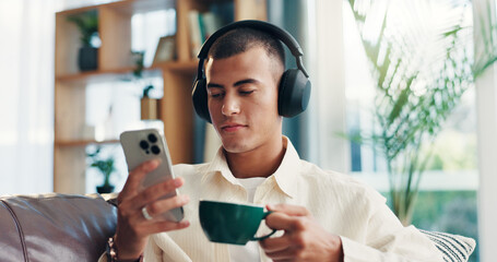 Home, man and coffee with mobile for music, wellness and comfortable on sofa in morning. House, male person and relax with headphones for listening sound, espresso and smartphone app for audio track