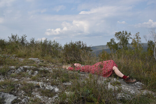 Woman rests peacefully on rocky terrain in a floral dress