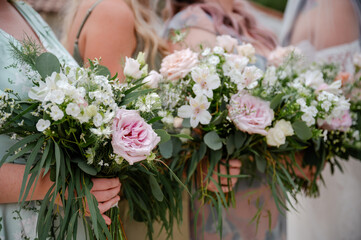 Bridesmaids holding white and pink bouquets of roses and wildflowers