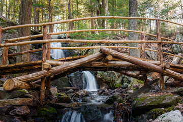 Fototapeta premium Rustic Wooden Bridge Over a Cascading Waterfall