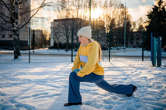 Woman stretching and performing a lunge outdoors in winter