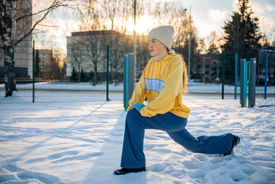 Woman stretching and performing a lunge outdoors in winter