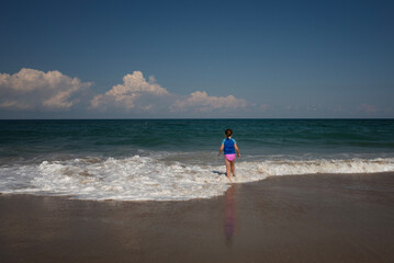 Behind young girl walking into waves Outer Banks North Carolina