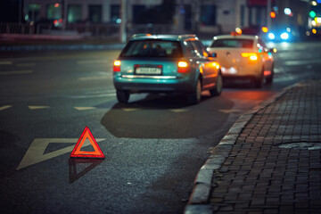 Nighttime road accident with warning triangle, rear end collision, alerting drivers to the dangers of traffic incidents and the importance of vehicle distance. Emergency warning sign on dark road