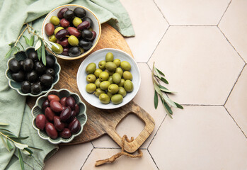 Green, black and kalamata olives in bowls on wooden board