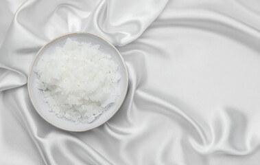 Magnesium flakes in a bowl resting on elegant white silk fabric