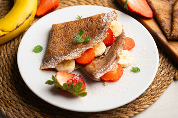 Chocolate crepes with fruit, strawberries and bananas.