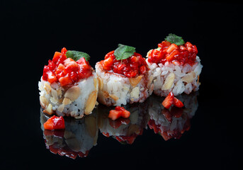 Sushi roll made of rice and cream cheese, garnished with fresh strawberries and mint leaf. Japanese sushi rolls on a black background with reflection.