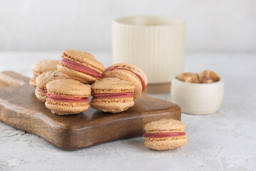 Caramel macaroons with raspberry cream and cup of coffee on a board. Vegan dessert. Sugar, lactose and gluten free.