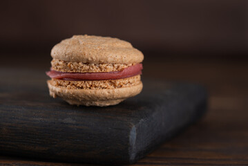 Vegan homemade caramel macaroons with raspberry cream on shea butter on a wooden board. Sugar, lactose and gluten free.