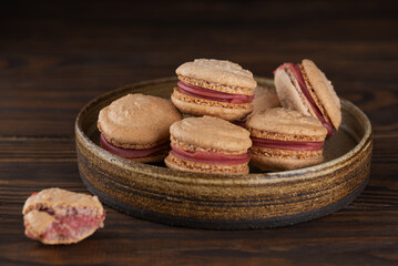 Vegan homemade French caramel macaroons with raspberry cream on shea butter on a wooden table. Sugar, lactose and gluten free.