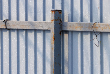 A rusted metal pole is attached to a fence