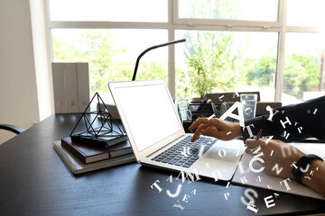 Woman with laptop writing in notebook at table, closeup