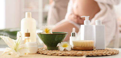 Bottles of cosmetic products with flowers on table in spa salon, closeup