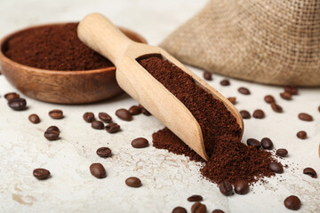 Scoop and bowl of coffee powder with beans on grunge table, closeup