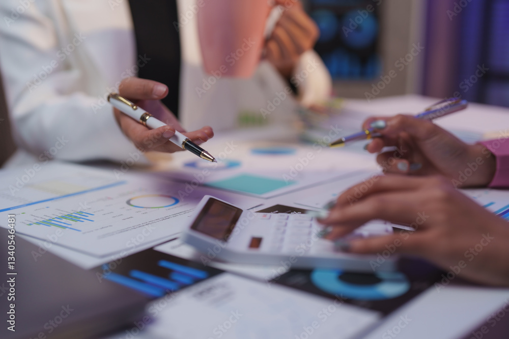Poster businesswomen are using calculator and pointing at financial reports while discussing and analyzing 