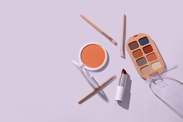 Set of cosmetic products and makeup brushes on light background