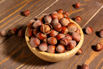 Bowl with shelled hazelnuts on wooden background