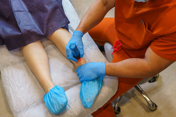 Doctor performing laser scar removal treatment on a patient's leg inside a medical clinic, enhancing skin appearance and promoting healing