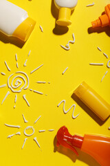 Drawings of suns made with sunscreen cream on yellow background