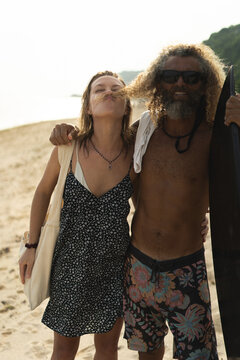 Friends with a surfboard having fun on the beach