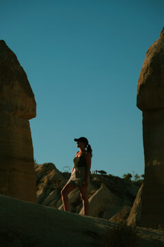 Woman looking at the sun between rock formations in Cappadocia