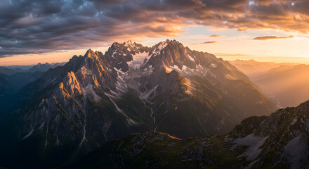Obraz premium Dramatic Mountain Range at Sunset with Golden Light and Cloudy Skies