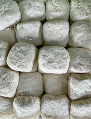 Square tofu pieces soaking in water sale on traditional market. That tofu showing their soft, textured surfaces and uniform arrangement.