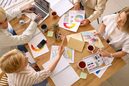 Team of graphic designers working with color palettes at table in office