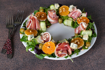 Wreath-shaped salad with jamon, tangerines, arugula, dor bleu cheese, cucumber and pine nuts
