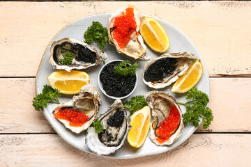 Plate of tasty oysters with lemon, black and red caviar on light wooden background