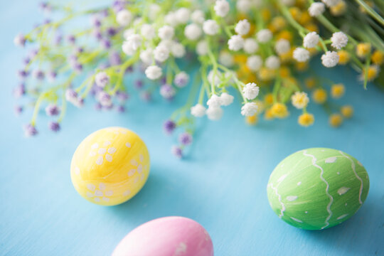 Easter eggs decoration with flowers on blue wooden table