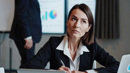 Businesswoman taking notes during a digital security meeting, focusing on cybersecurity strategies and data protection
