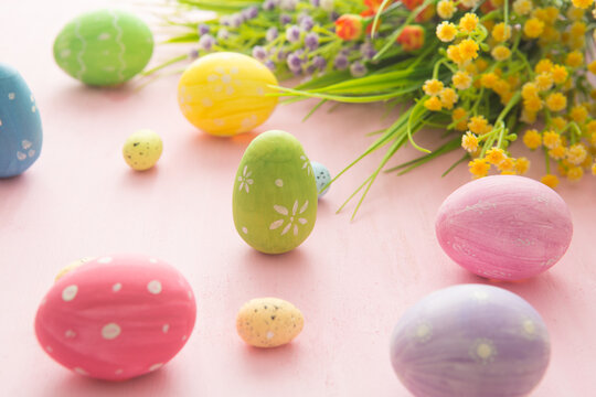 Easter eggs with wild flowers on a wooden pink table background