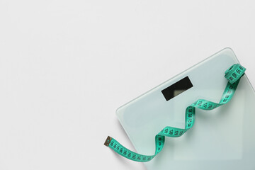 Scales with turquoise measuring tape on white background
