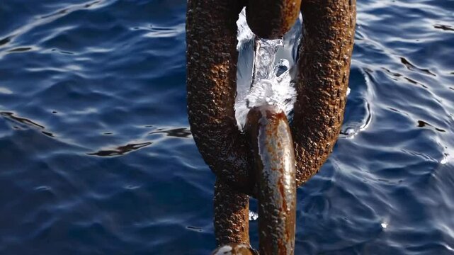 Rusty maritime anchor chain sinking through deep blue ocean waters, revealing weathered metal texture and nautical industrial strength