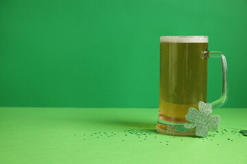 Glass of beer and clover on green background. St. Patrick's Day celebration