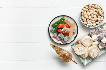 Composition with traditional Eastern sweets and Aladdin lamp for Ramadan on light wooden background